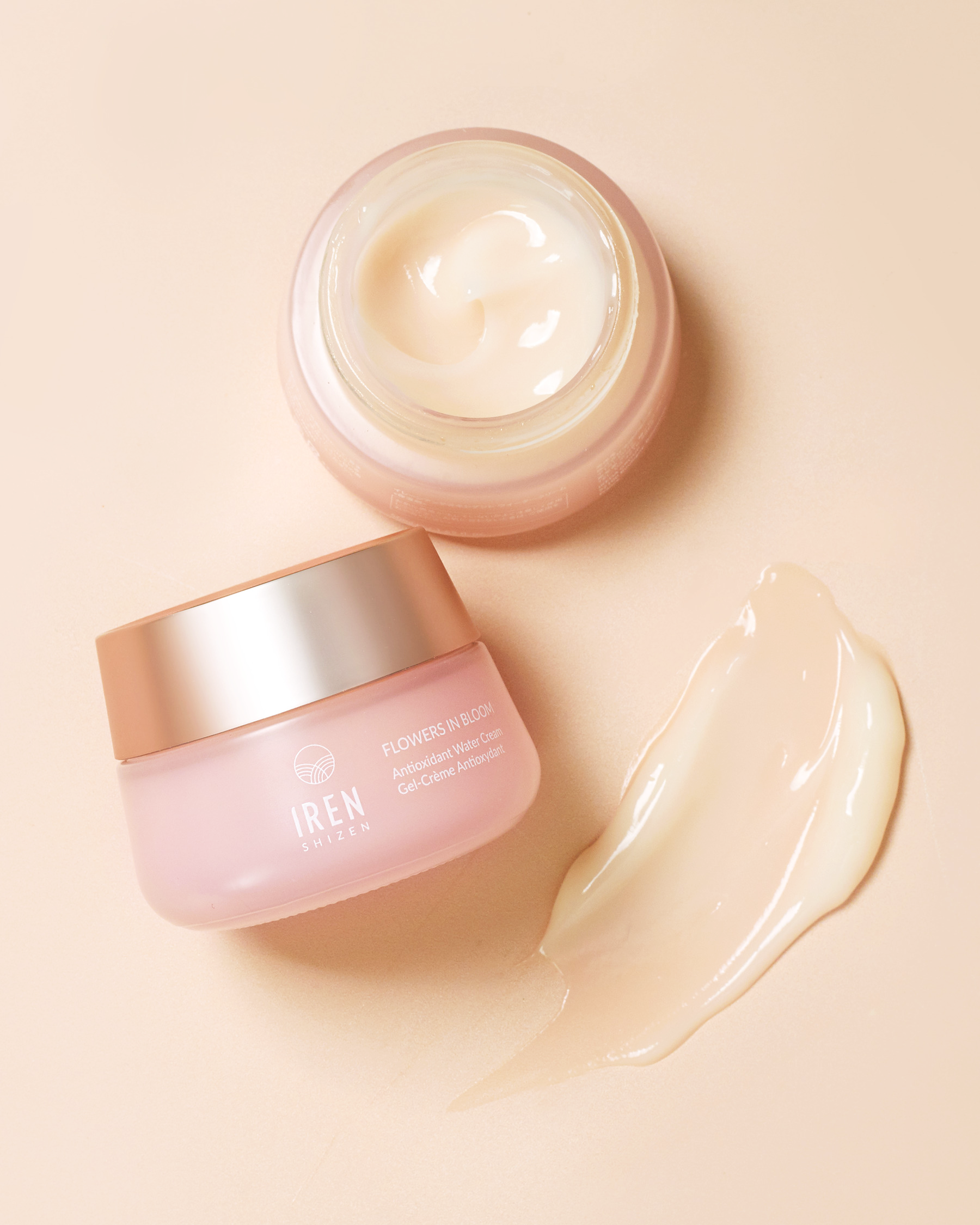 Jar of FLOWERS IN BLOOM Antioxidant Water Cream with a sample of the product beside it on a peach-colored background, formulated for sensitive skin by IREN Shizen. #all-groups