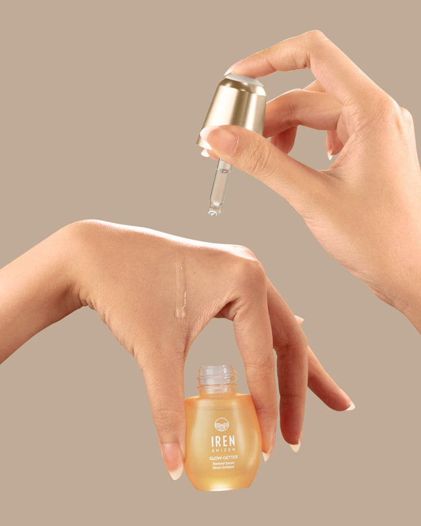 A woman's hand is holding a customised bottle of IREN Shizen GLOW-GETTER Renewal Serum.