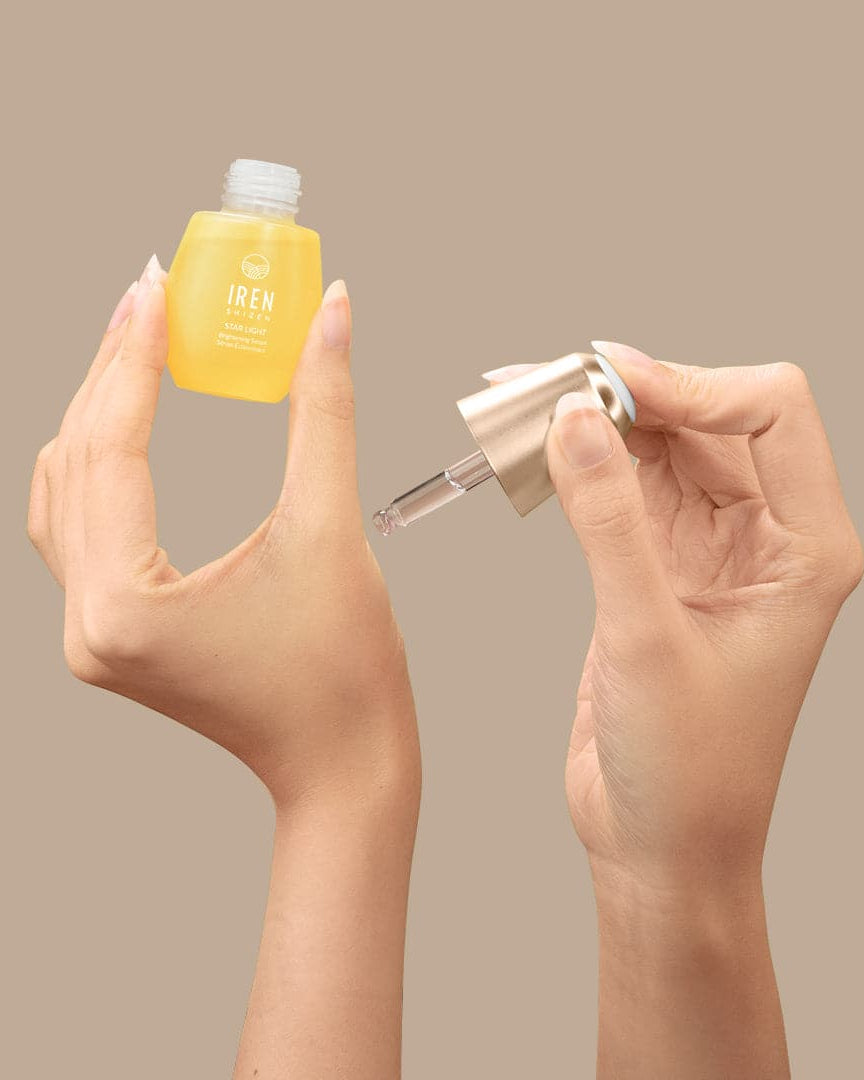 A woman's hands holding a small bottle of customised IREN Shizen STAR LIGHT Brightening Serum.