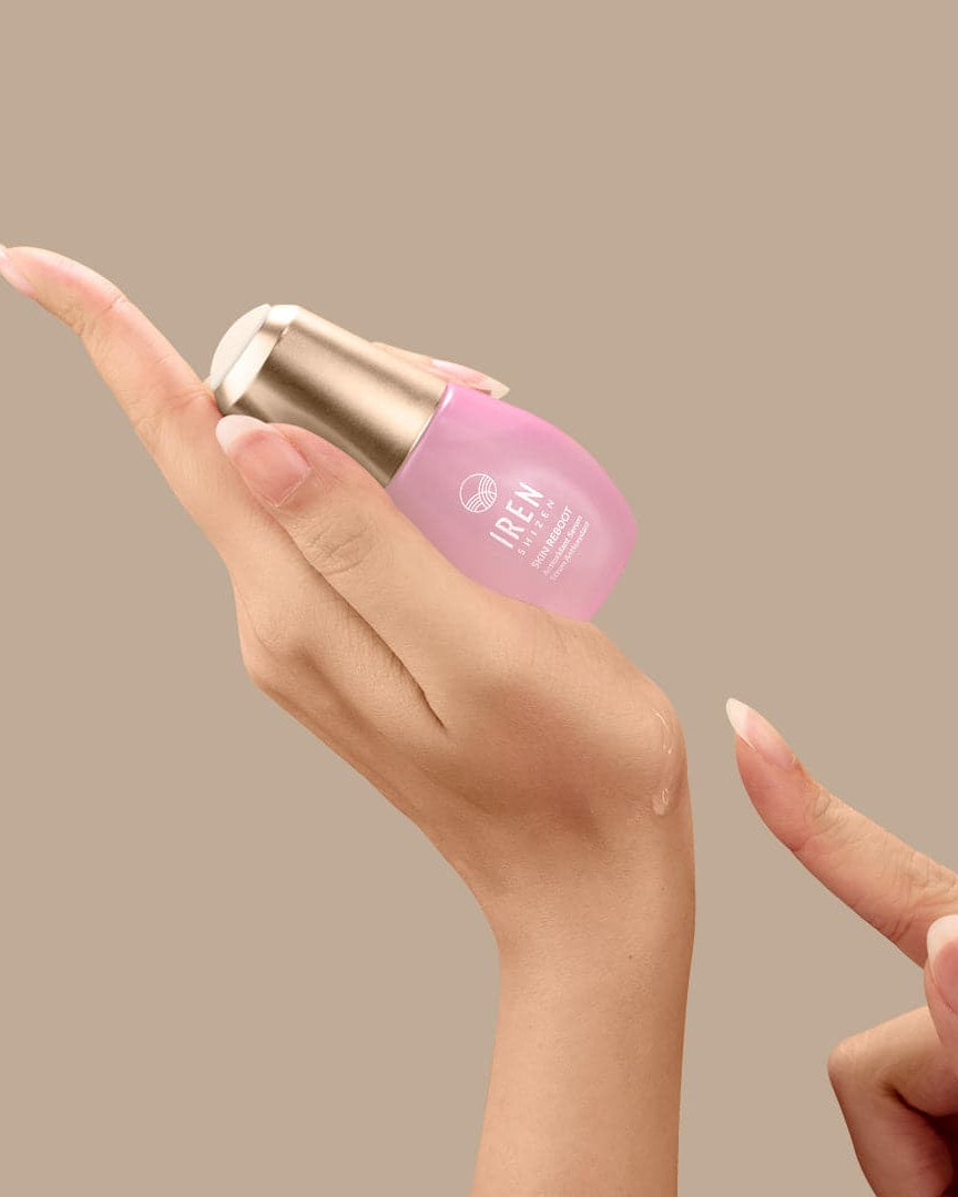 A woman's hand holding a bottle of customized Japanese skincare serum by IREN Shizen.