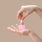 A woman's hand delicately holding a small bottle of IREN Shizen's GLOW UP Facial Oil + Serums.