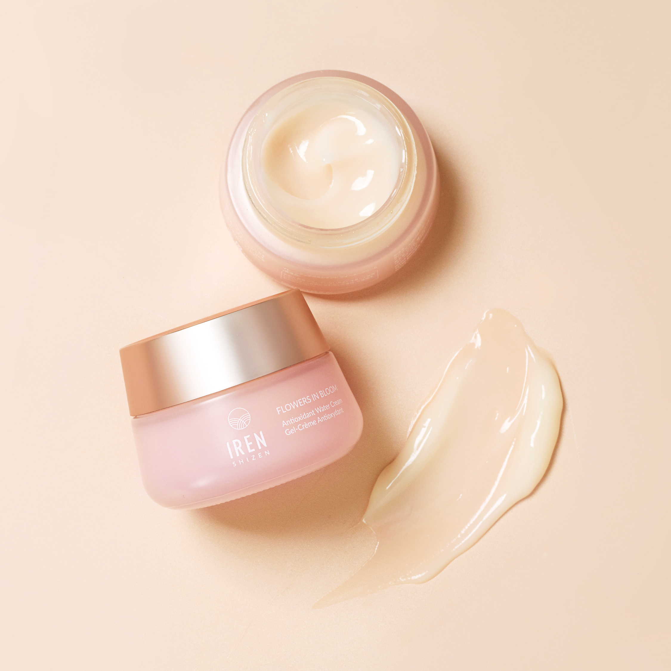 Jar of FLOWERS IN BLOOM Antioxidant Water Cream with a sample of the product beside it on a peach-colored background, formulated for sensitive skin by IREN Shizen. #all-groups