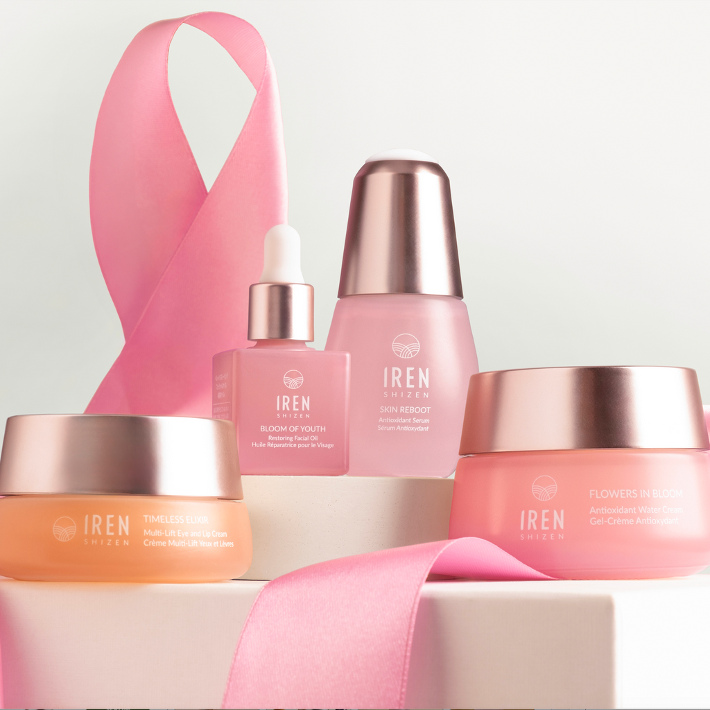 A display of the PINK OCTOBER Skincare Set, featuring bottles and jars elegantly framed by a pink ribbon, promotes Breast Cancer Awareness. Each product bears the IREN Shizen brand name and promises a youthful, glowing complexion.