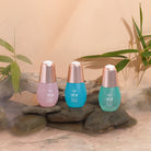 Three cosmetic bottles from the MOCHI SKIN Instant Glow Travel Set by Fast Bundle are set on rocks amidst greenery and mist.