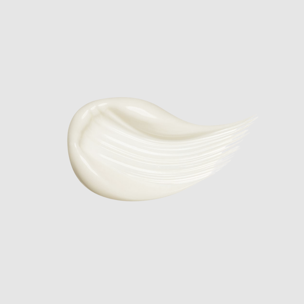 A smear of white cream with a smooth, glossy texture on a light grey background, infused with Bakuchiol for an anti-aging elixir that aims to reduce dark circles, is presented in the TIMELESS ELIXIR Multi-Lift Eye and Lip Cream by IREN Shizen.