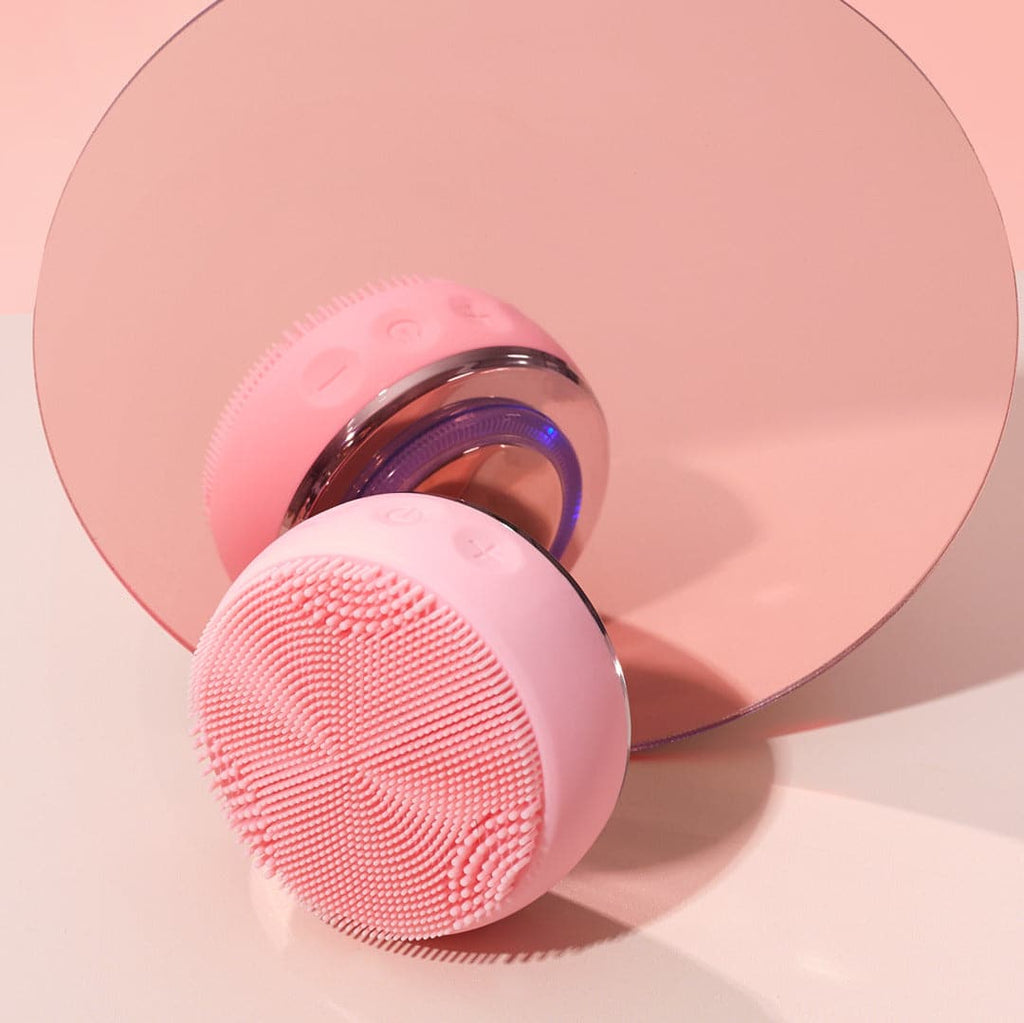 A pink Pro-Collagen Set brush for AGE DEFENSE beauty, inspired by Japanese skincare, placed on a mirror.