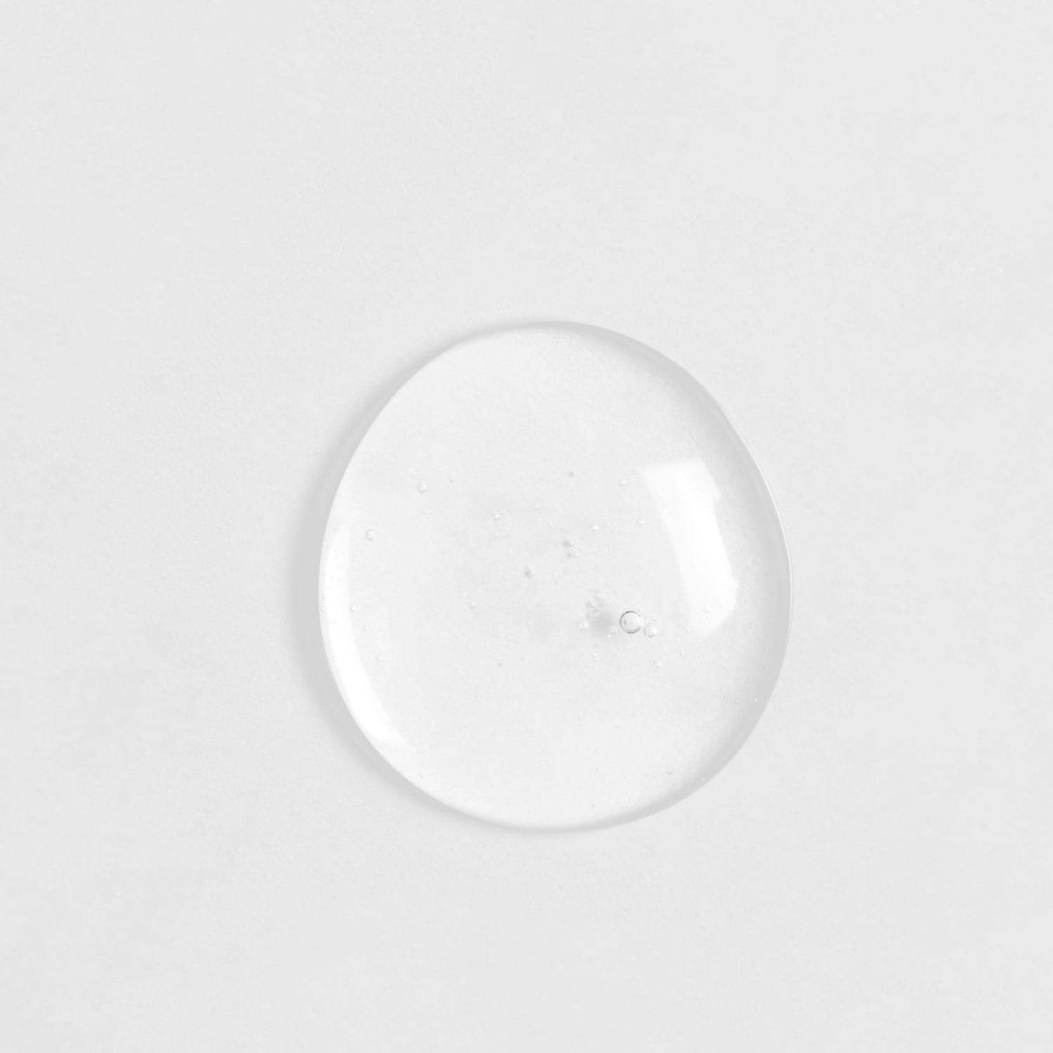 A clear glass ball of customised SKIN REBOOT Antioxidant Serum on a white surface by IREN Shizen.